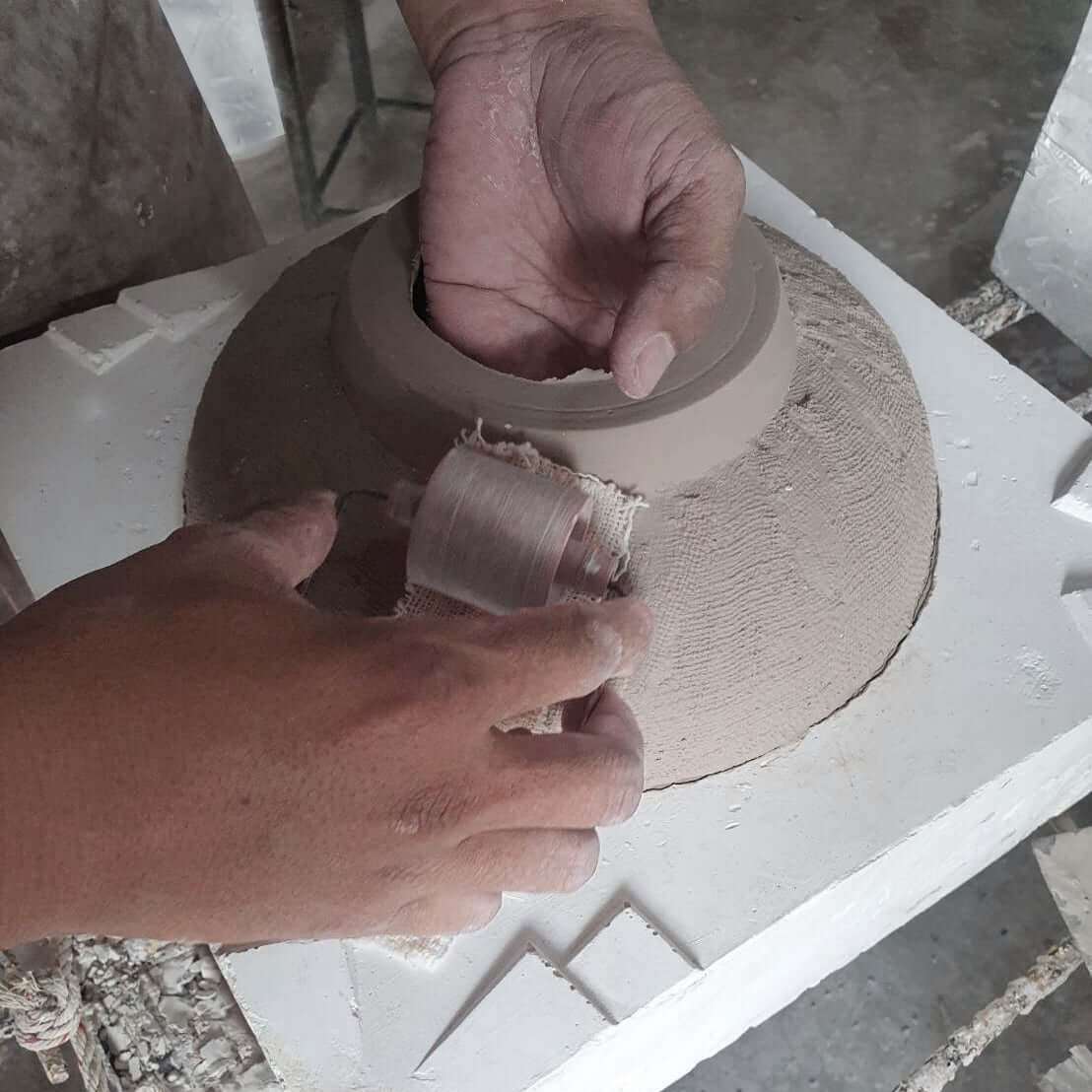 Person working with clay on a pottery wheel, making handmade ceramic vase with unique texture