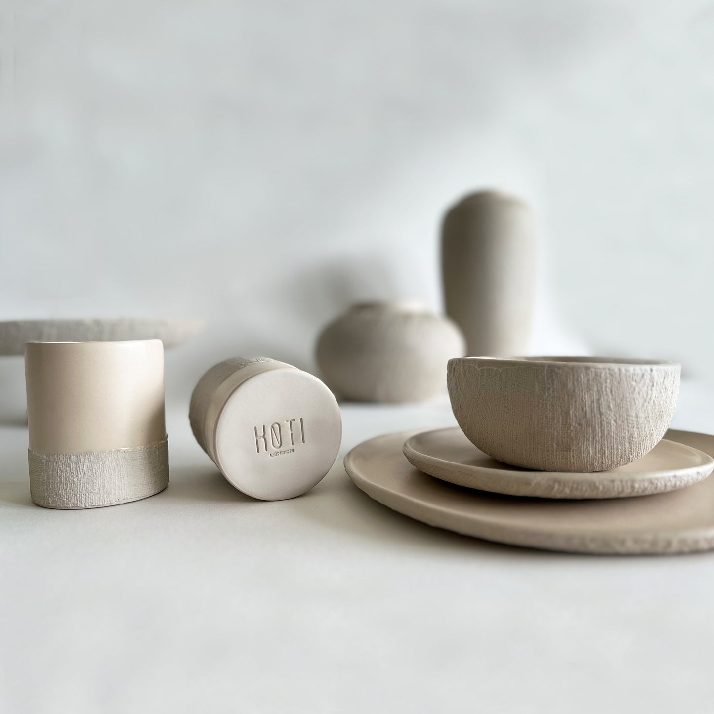 beige matte handcrafted ceramic dinnerware set, japandi tableware of large plates, small plates, bowl, cups, serving tray, serving spoon, vases