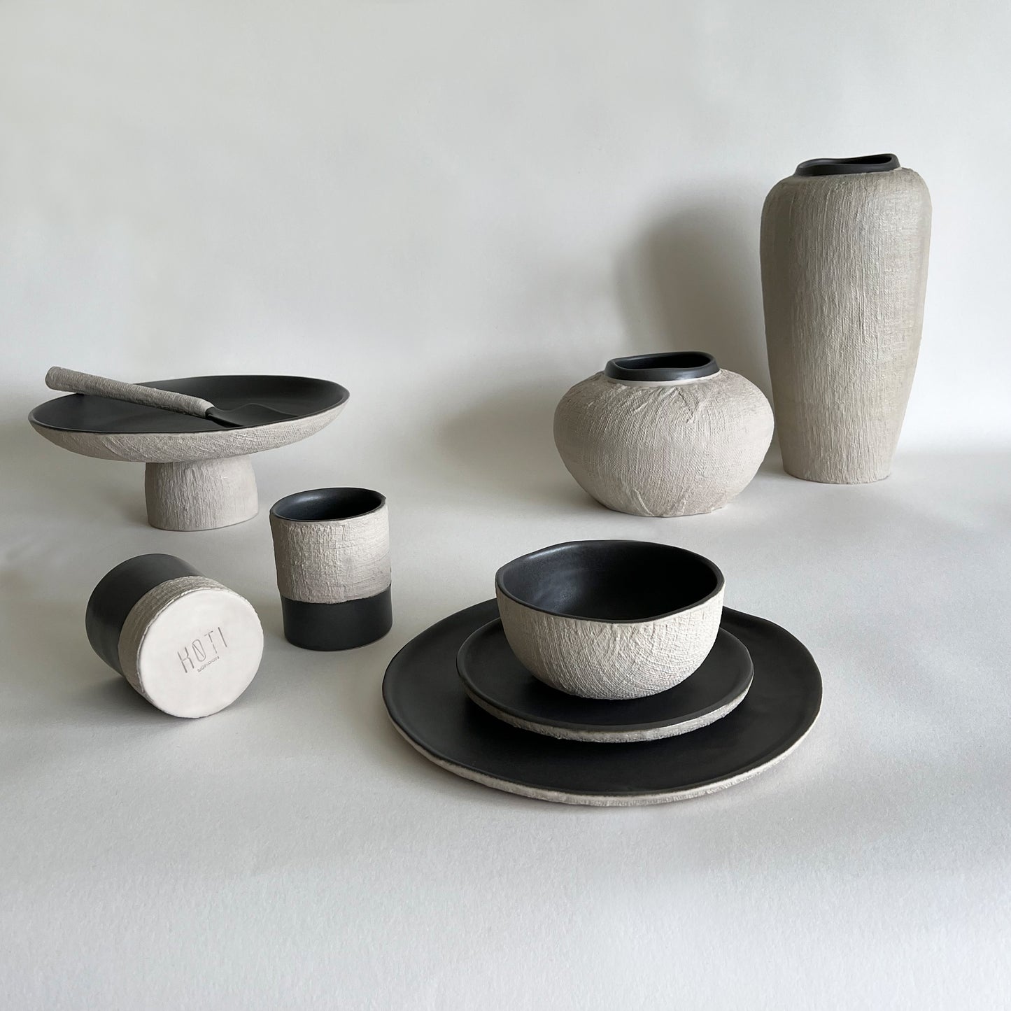 beige and charcoal handmade ceramic tableware set of dinner plate, starter plate, soup bowl, ceramic cups, serving platter, serving salad spoons, ceramic large vase, ceramic medium vase