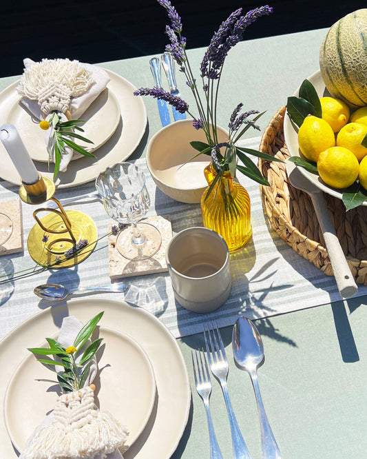 beautiful tablescape using handmade ceramic dinnerware with fruit platter, plates, and cutlery al fresco.
