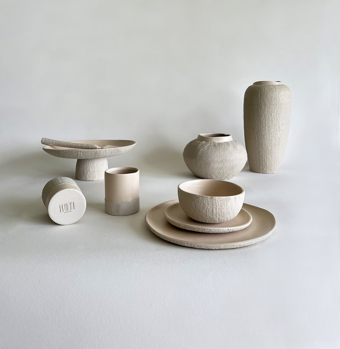 beige matte textured handmade ceramic tableware set of large plate, small plate, bowl, cups, serving tray, serving spoon, ceramic large vase, ceramic medium vase