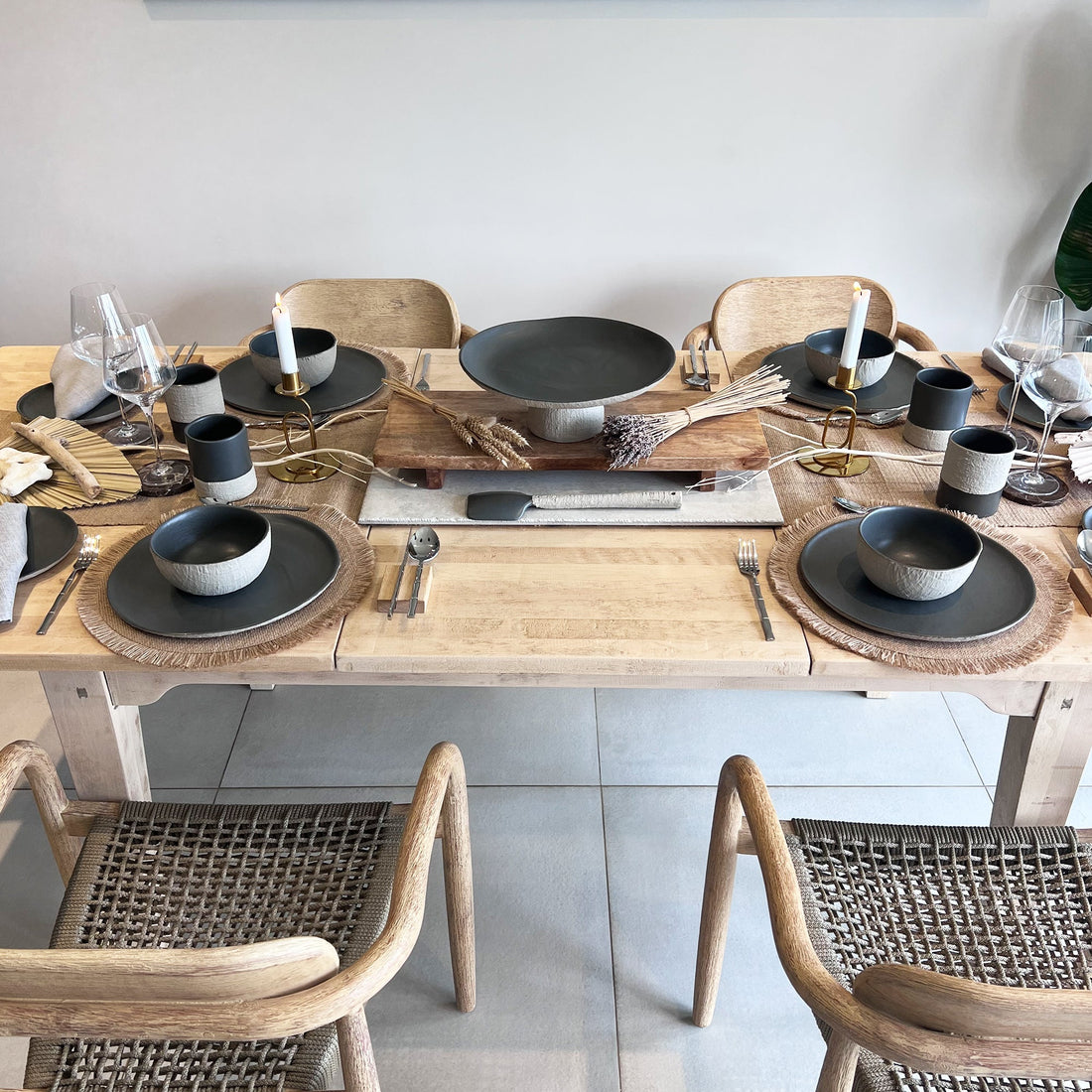 dining tablescape showcasing handmade ceramic dinnerware set, using plates, bowls, cups, mugs, serving trays and serving spoon. Rustic feel, displayed on large wooden table, implemented with natural tones,