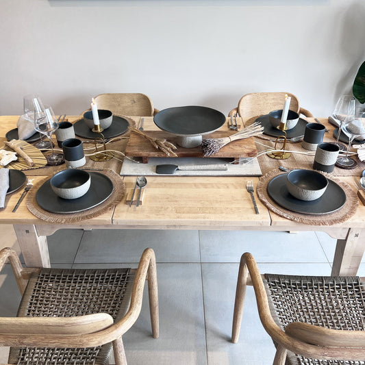 dining tablescape showcasing handmade ceramic dinnerware set, using plates, bowls, cups, mugs, serving trays and serving spoon. Rustic feel, displayed on large wooden table, implemented with natural tones,