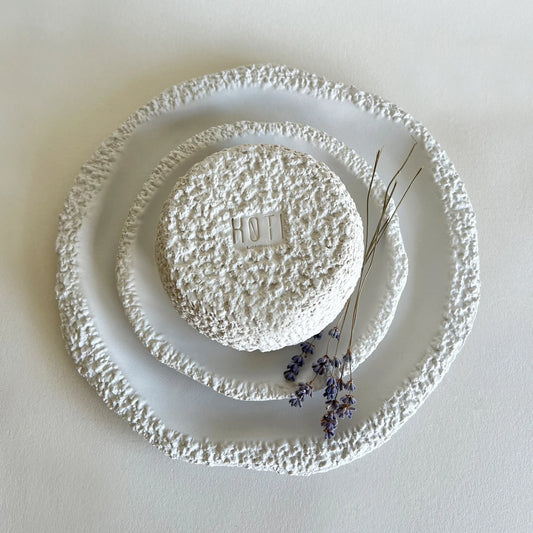 Three textured white ceramic plates and bowl, styled with dried lavender sprigs 