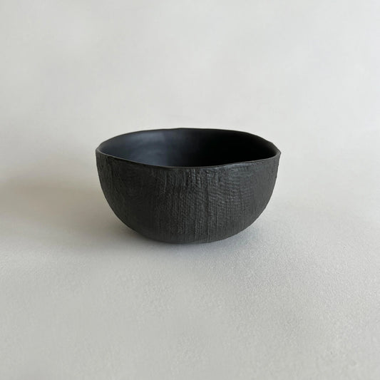 A  handmade soup or breakfast  ceramic bowl with a dark black textured exterior and a smooth black interior.