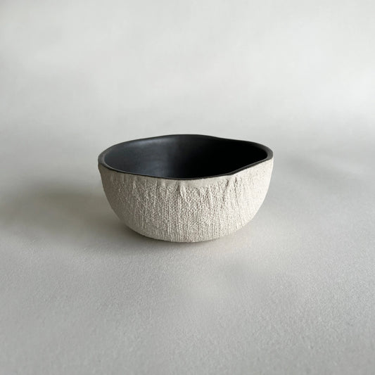 Cereal or soup handmade ceramic bowl in matte charcoal colour, contrasted with beige organic texture.