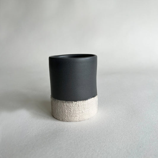 Organically shaped handmade ceramic mug in satin dark grey colour contrasted with woven texture.