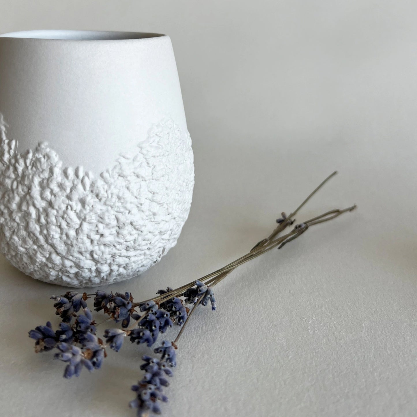 a close up detail of raw organic texture from handmade ceramic white cup