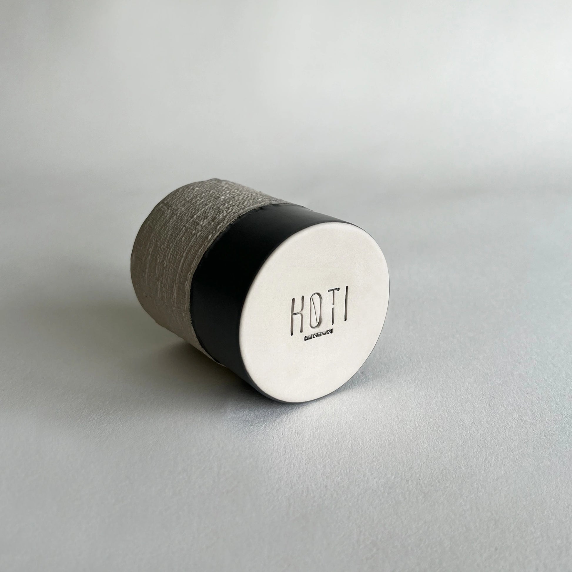 Organic ceramic cup in contrasted matte dark grey colour with beige texture.