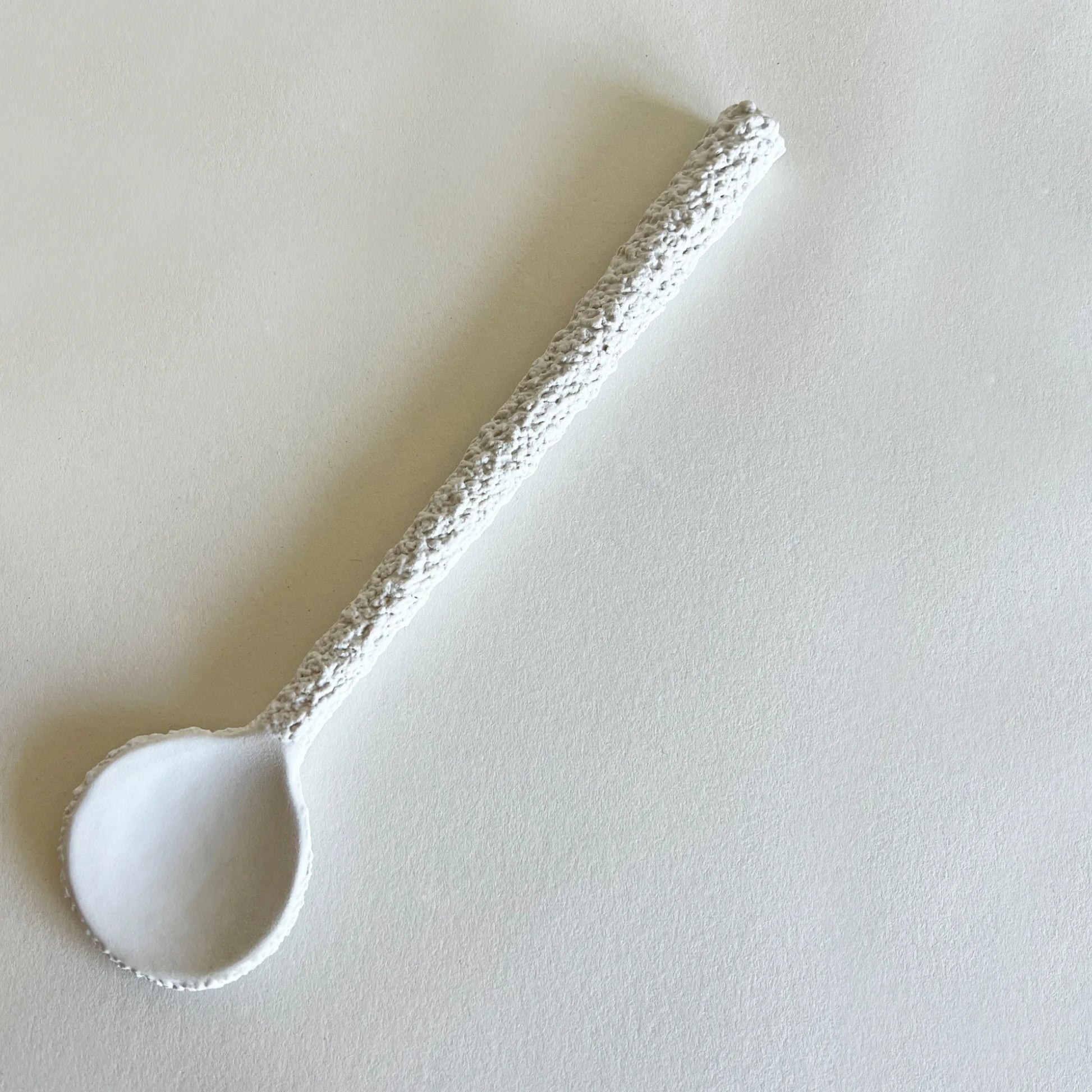 A large white ceramic serving spoon with a textured handle.