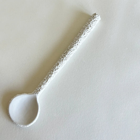 A large white ceramic serving spoon with a textured handle.