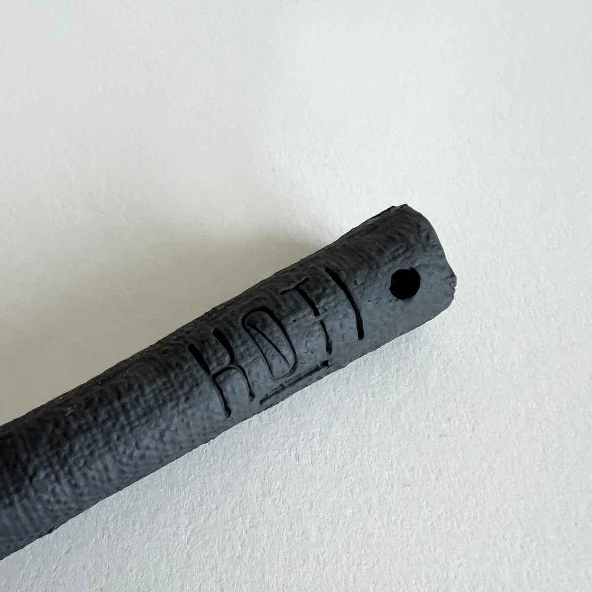 A close-up of a matte black ceramic serving spoon, showcasing the textured handle. 