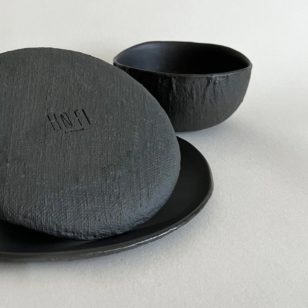Set of 3 black matte ceramic dinner plate, side plate and matching soup bowl in linen organic textured finish.  