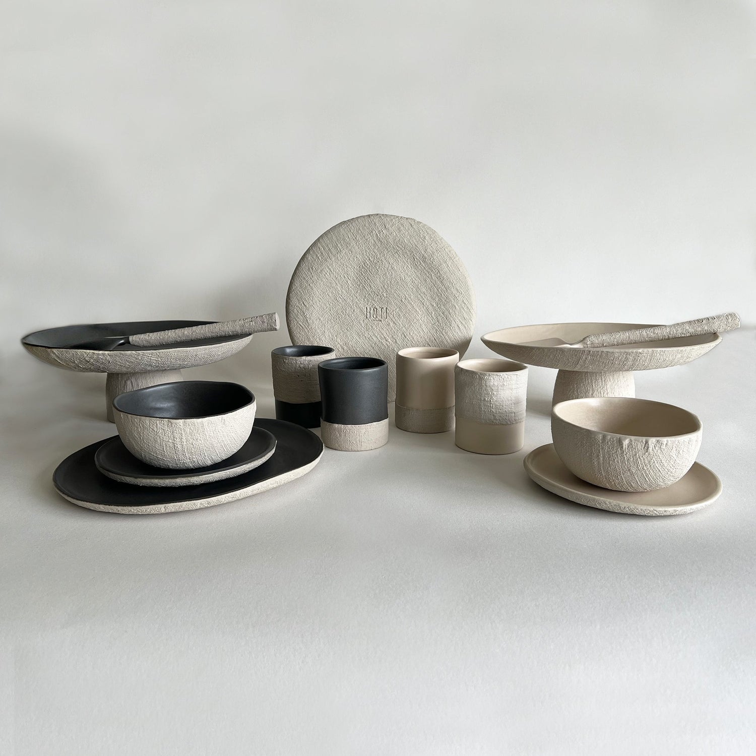 handmade ceramic dinnerware set of beige and black plates bowls and cups 