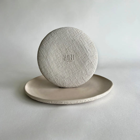 A round beige textured organic ceramic dinner plate and dessert plate showcasing the details .