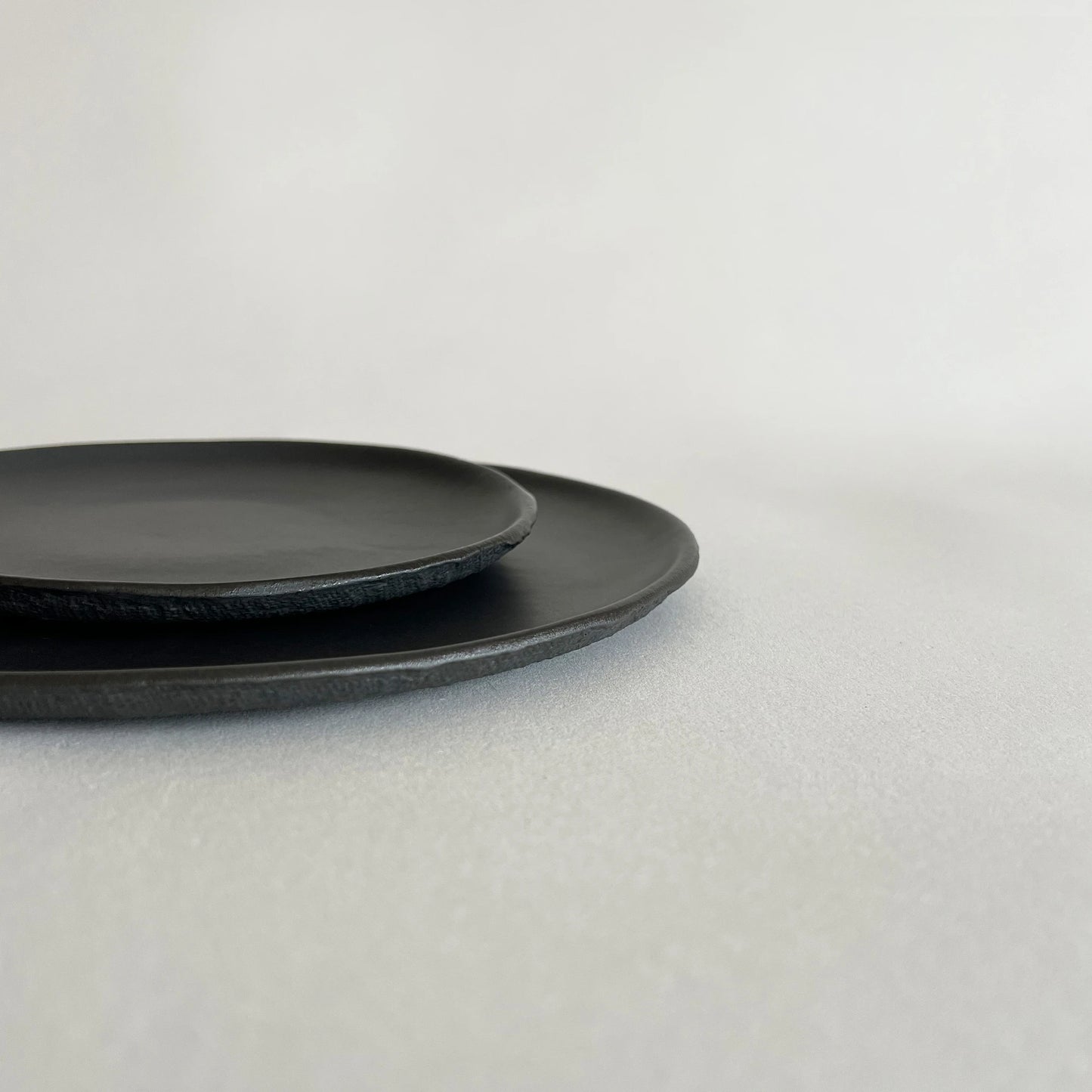 Set of two matte black textured pizza dinner plate and matching side or salad plate. 