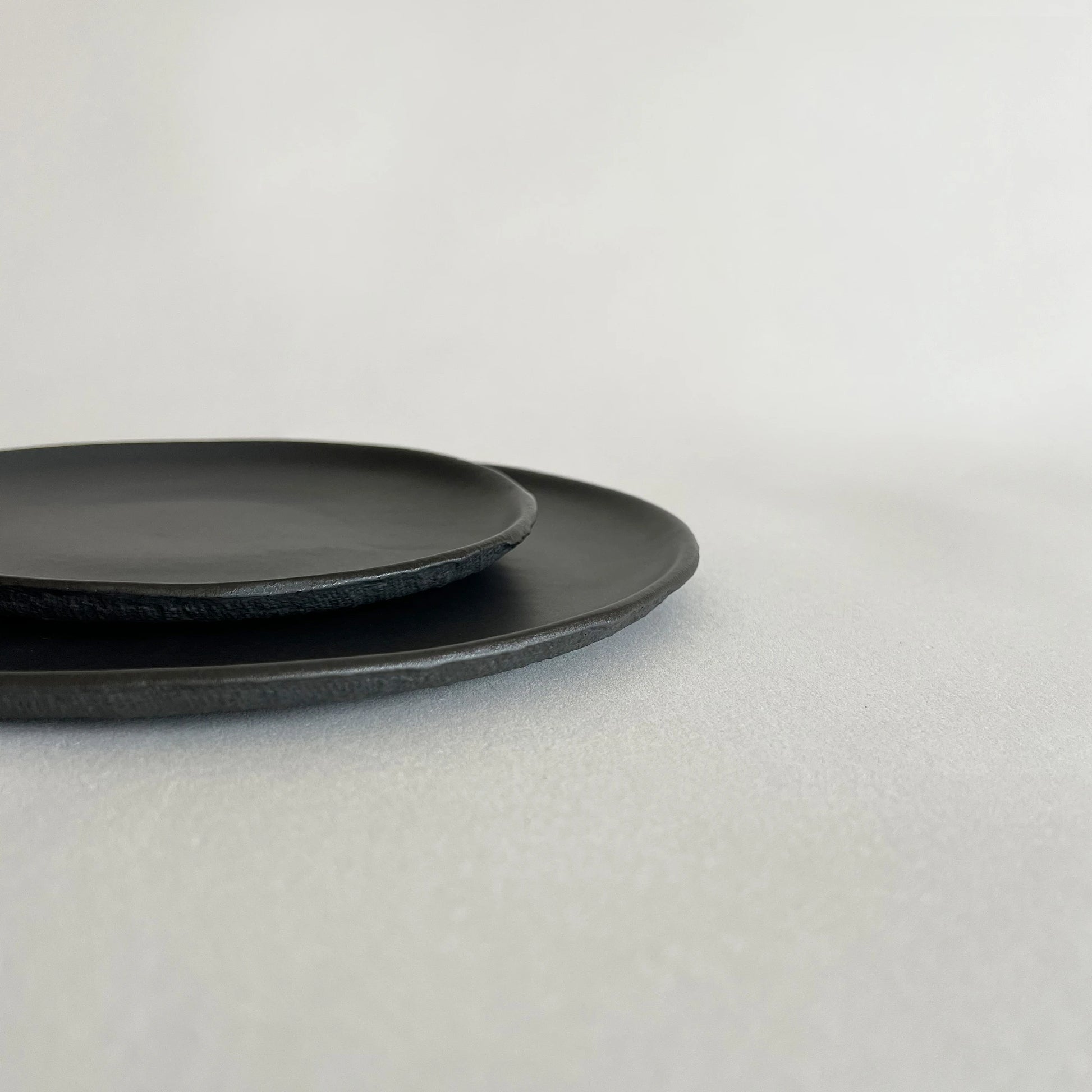 Set of two matte black textured pizza dinner plate and matching side or salad plate. 