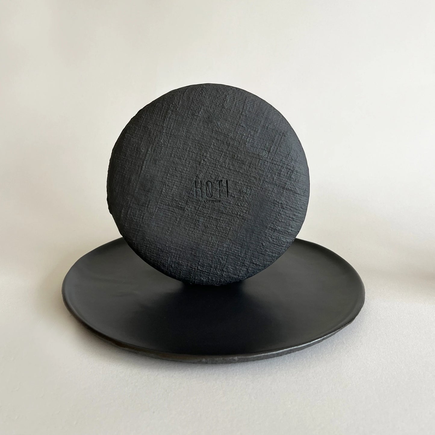 A round textured matte black large dinner plate and black textured side plate, showcasing organic linen texture. 