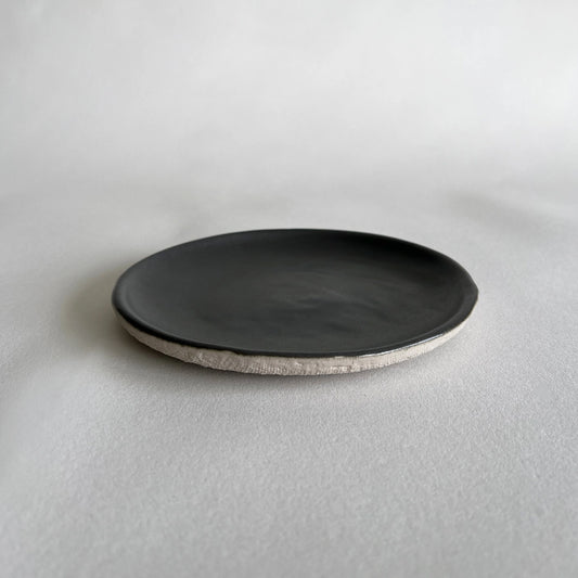 Side and dessert ceramic plate in matte charcoal colour contrasted with beige organic texture.