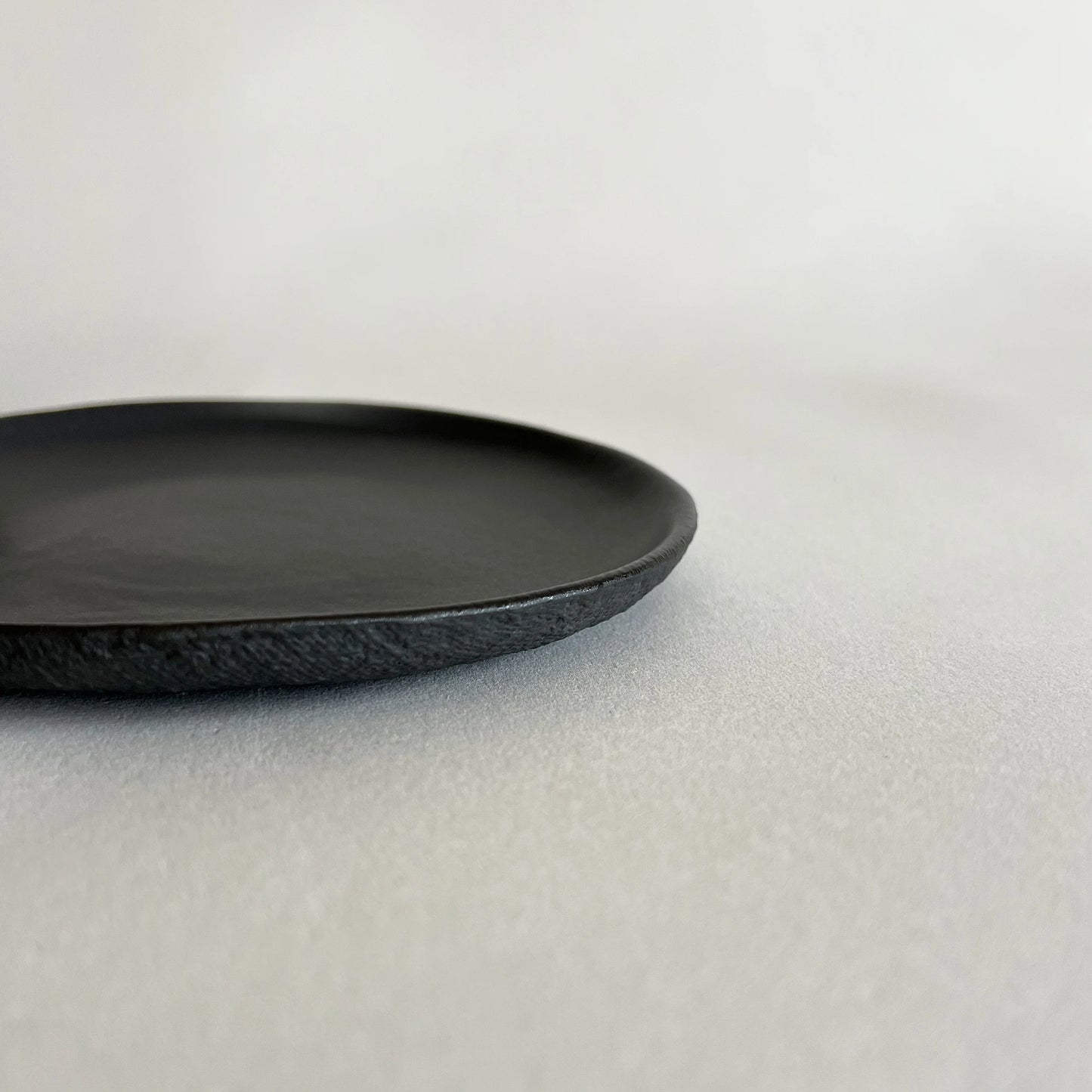 Dessert matte black ceramic plate with a textured, hand-painted finish.