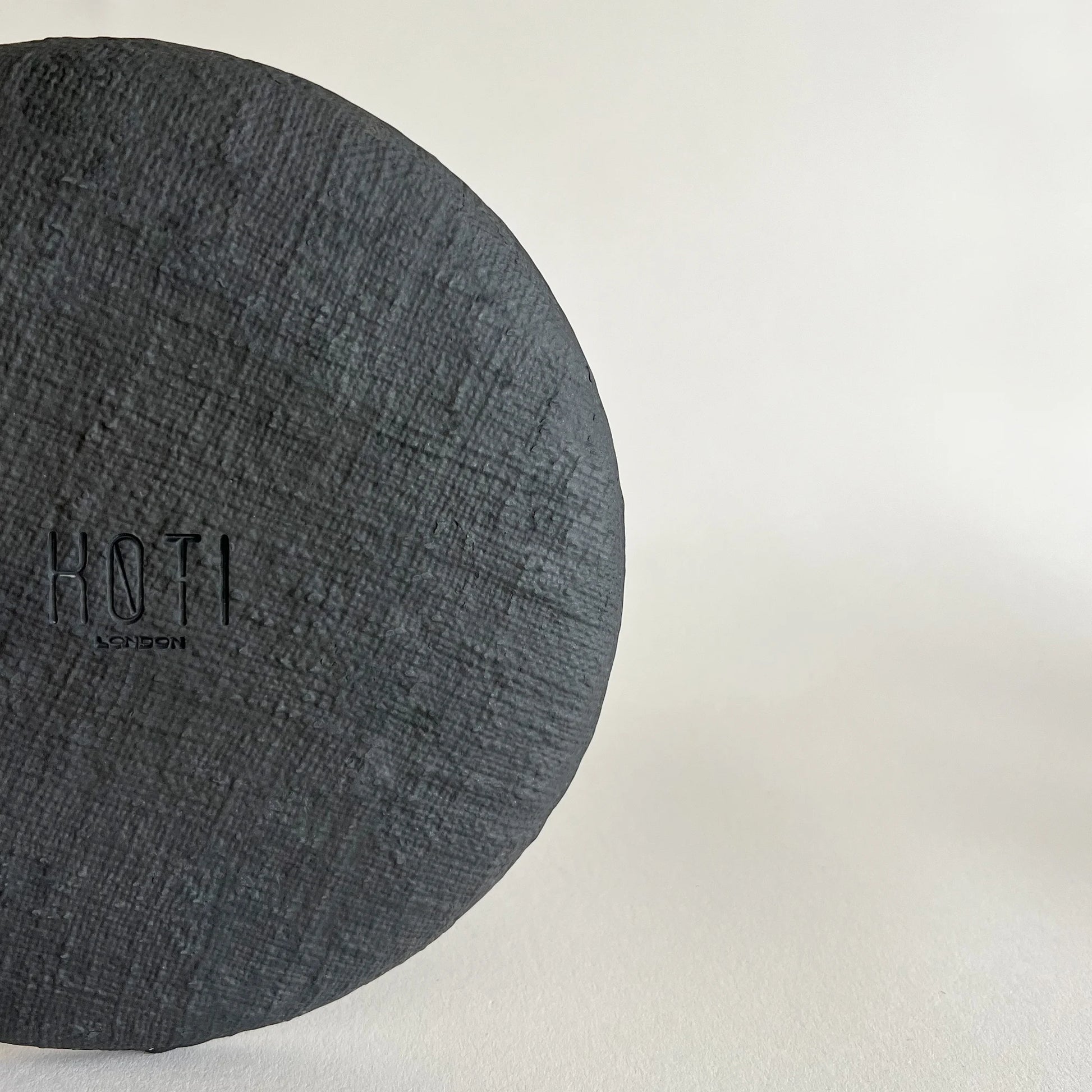 A close-up of a matte black textured ceramic salad plate.  