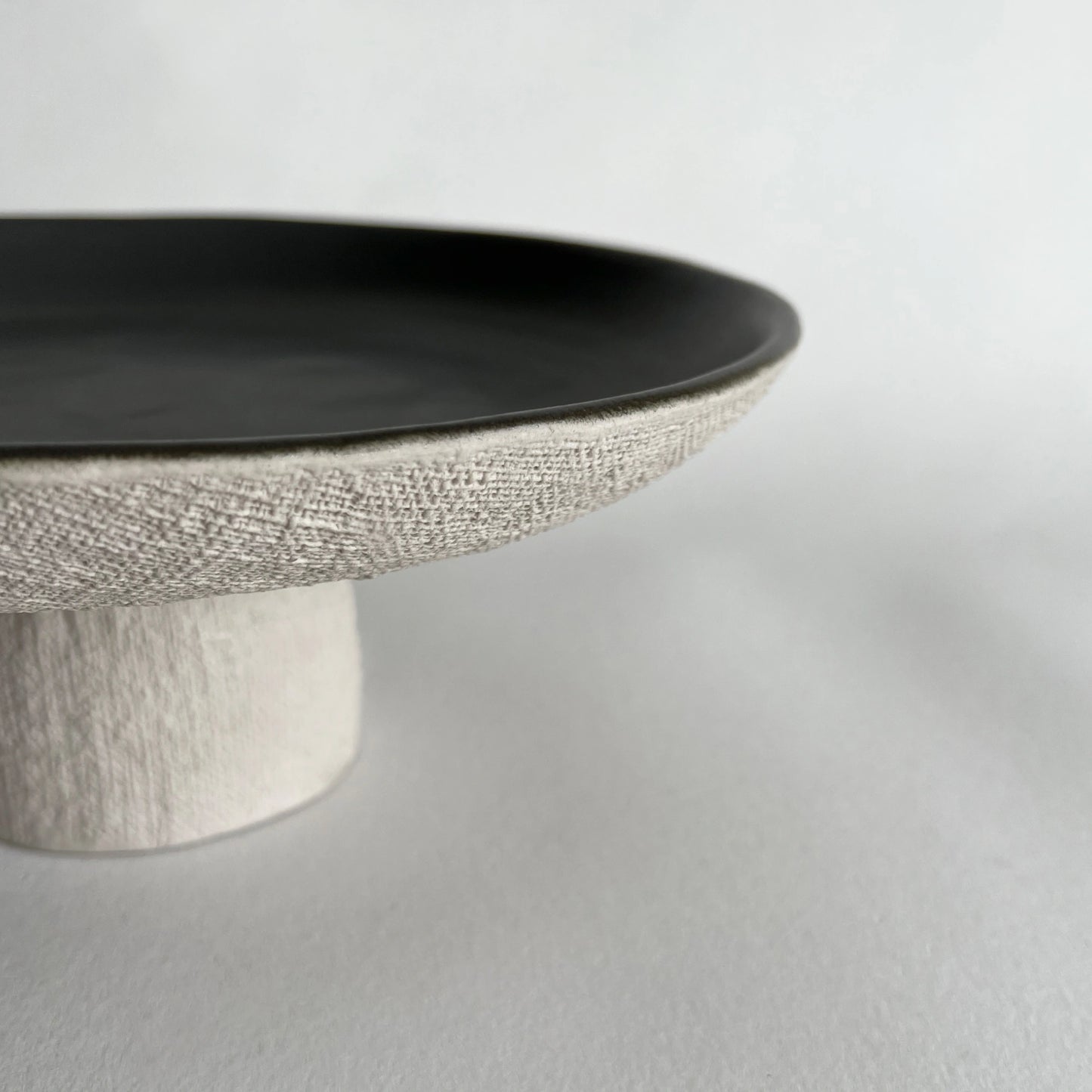 organically shaped textured finish on pedestal serving tray, in ceramic.