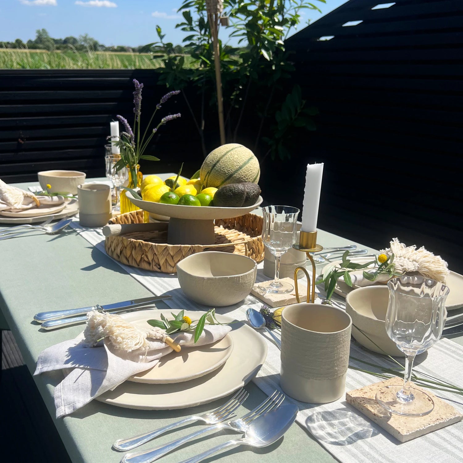 outdoor table setting in sage and beige colours using earthy ceramic dinnerware set with plates cups and bowls and serving platter