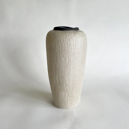 Tall handmade ceramic vase in organic and rustic texture in beige colour, contrasted with satin dark grey rim.